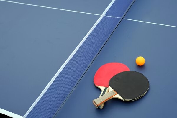 Palas y pelota sobre mesa de tenis de mesa azul